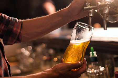 Persona llenando un vaso de cerveza en unbar