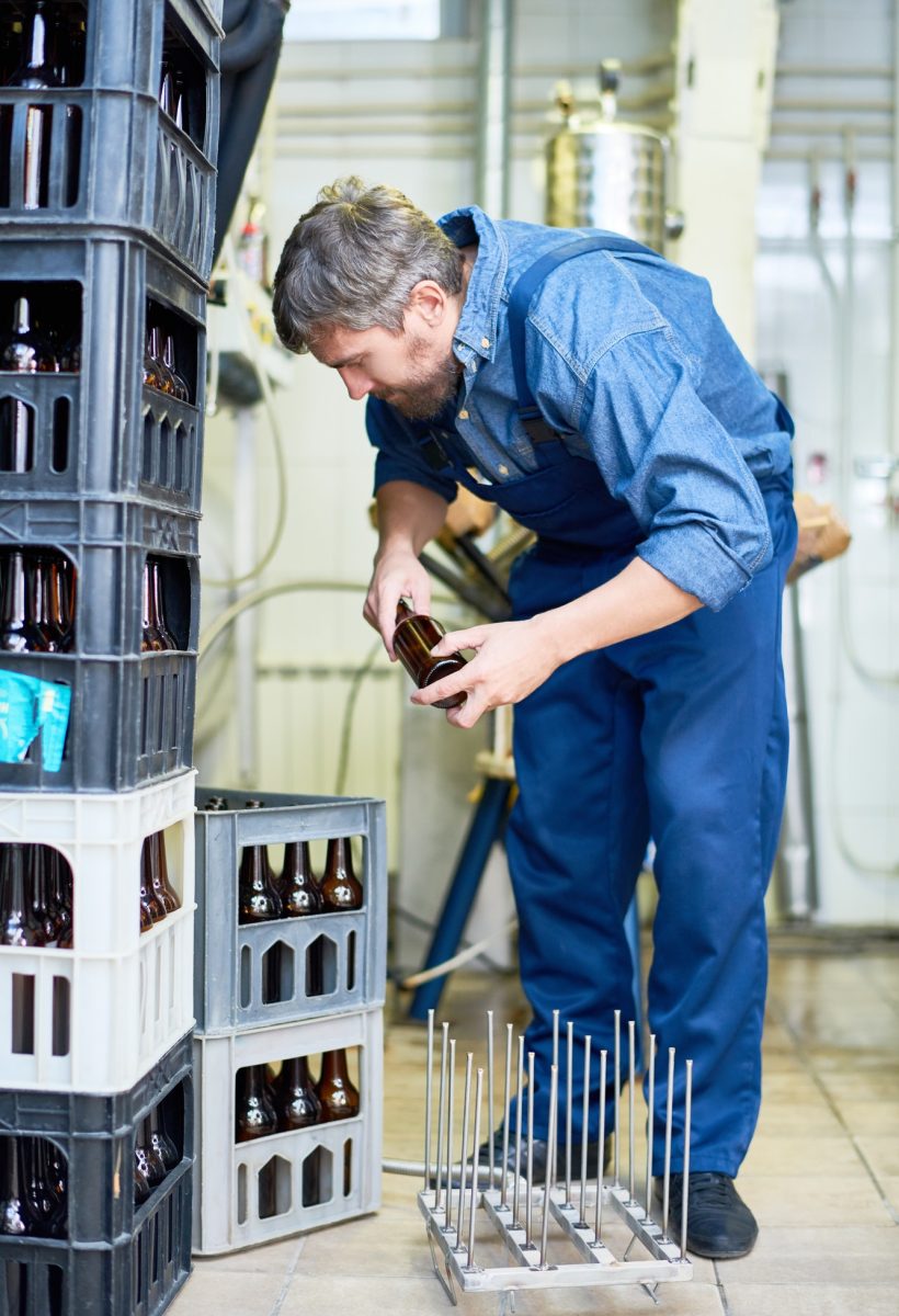 Hombre preparando botellas de cerveza en la bodega